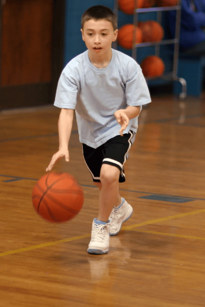 A boy dribbles a basketball as a way to showcase sports skills during a talent show. 